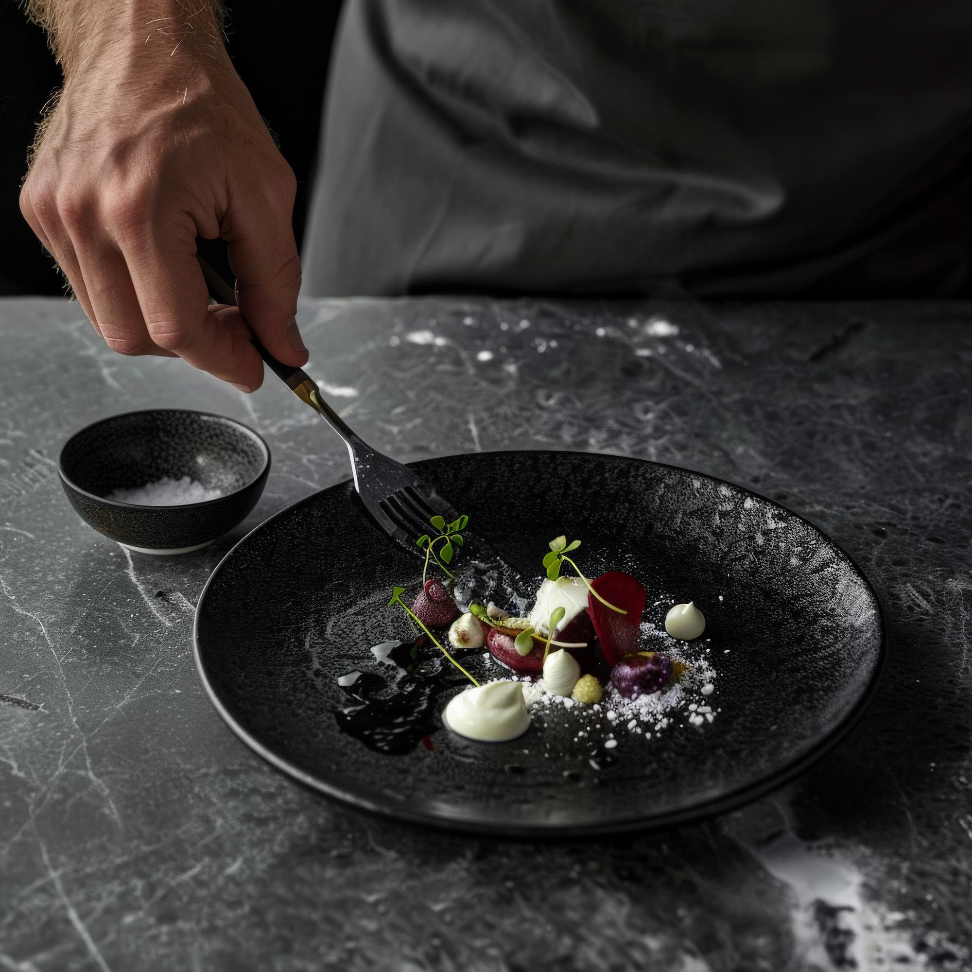 Chef plating a gourmet dish on a dark slate